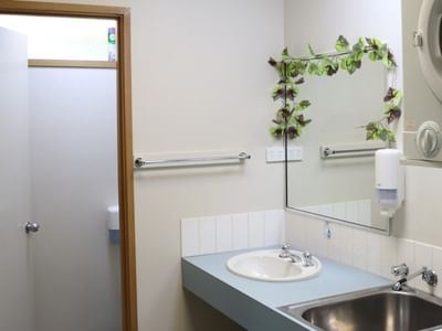 Bathroom with open shower stall, sink, mirror, and washing machine visible.