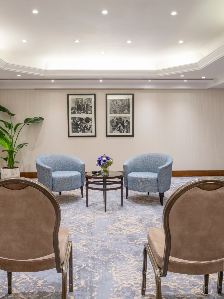 Blue armchairs by a small table under recessed lighting near chairs in Seminars & Banquets at Warwick Paris Champs Elysées