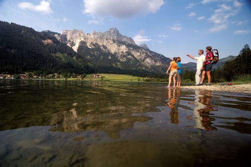 Children are standing near the lake with the mountain view of th
