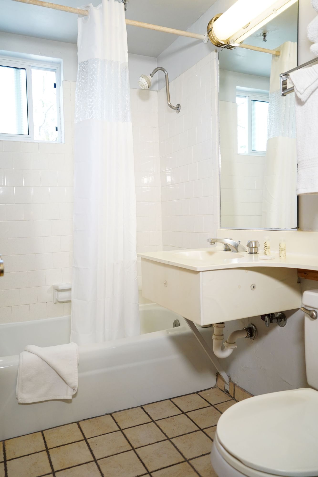 A standard hotel bathroom with a tub, shower curtain, sink, and toilet.