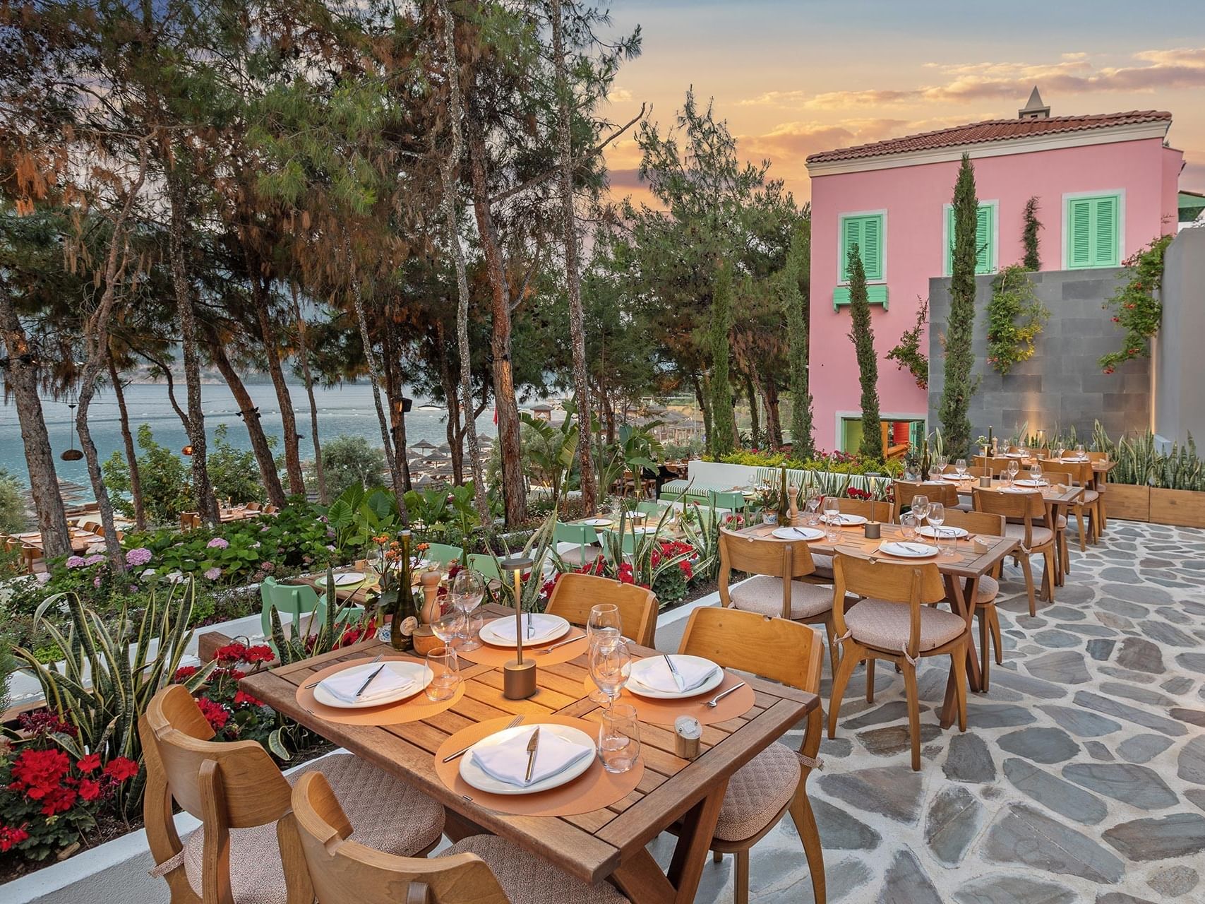 Coastal-view open-air restaurant at Titanic Luxury Collection Bodrum, with gracefully arranged tables in the evening sun.