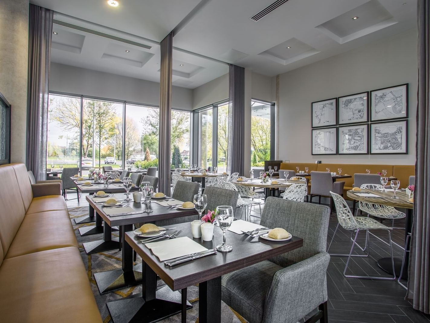 Glass House Restaurant with elegant tables and plush seating by large windows overlooking greenery at Heston Hyde Hotel