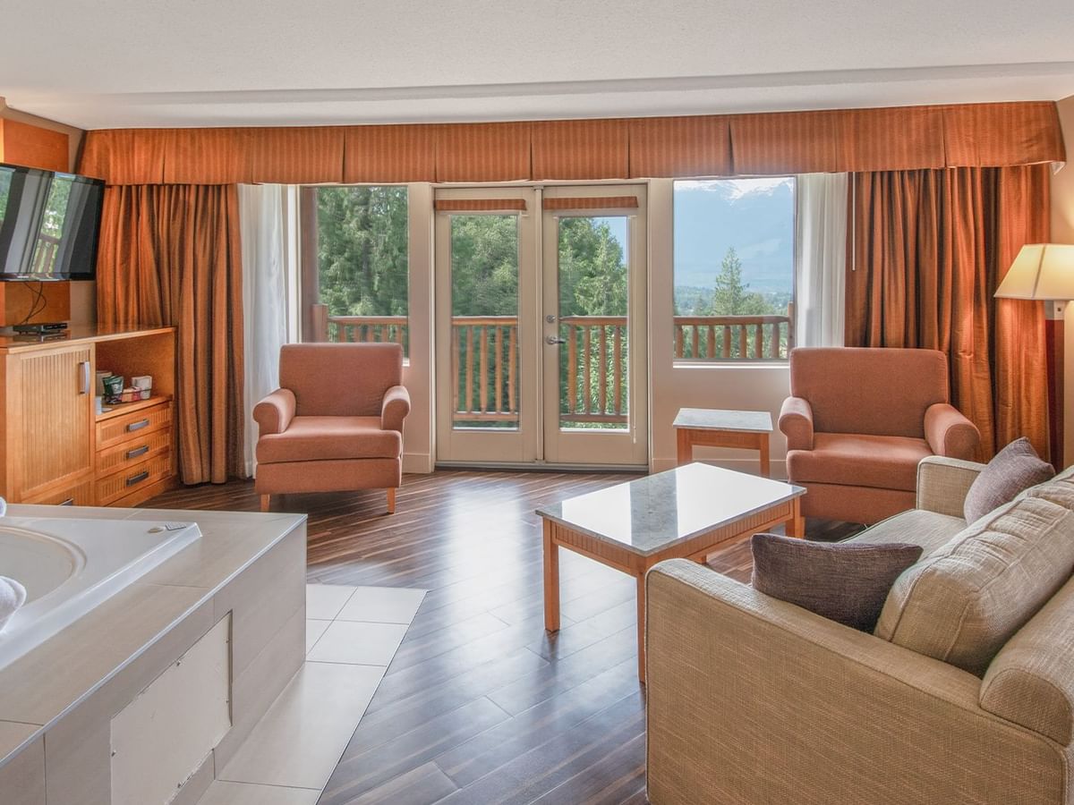 Hotel suite with couches, TV, and a jetted tub