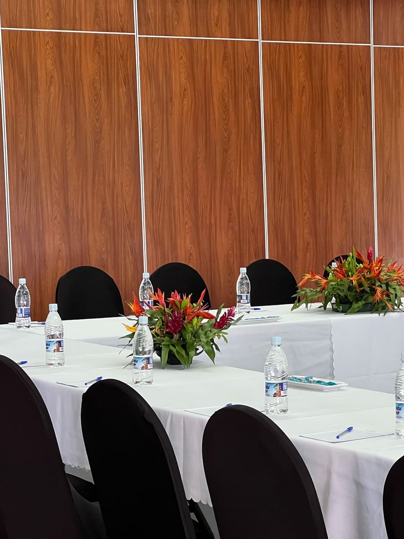 Long white table by black chairs and tropical flowers in Marquee Meeting Room Warwick Le Lagon Port villa