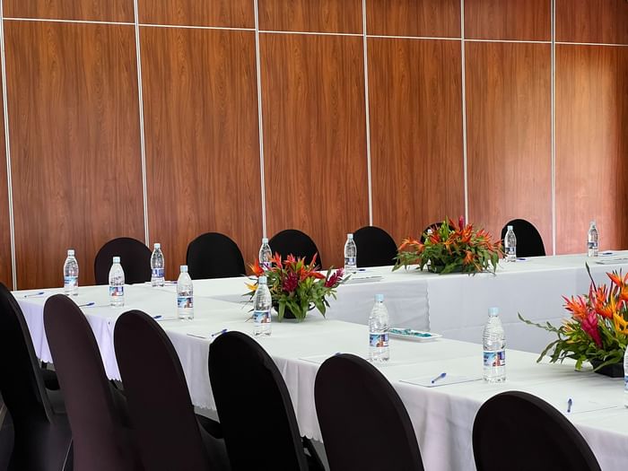 Long white table by black chairs and tropical flowers in Marquee Meeting Room Warwick Le Lagon Port villa