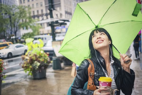 Woman smiling, drinking coffee and holding a lime green umbrella