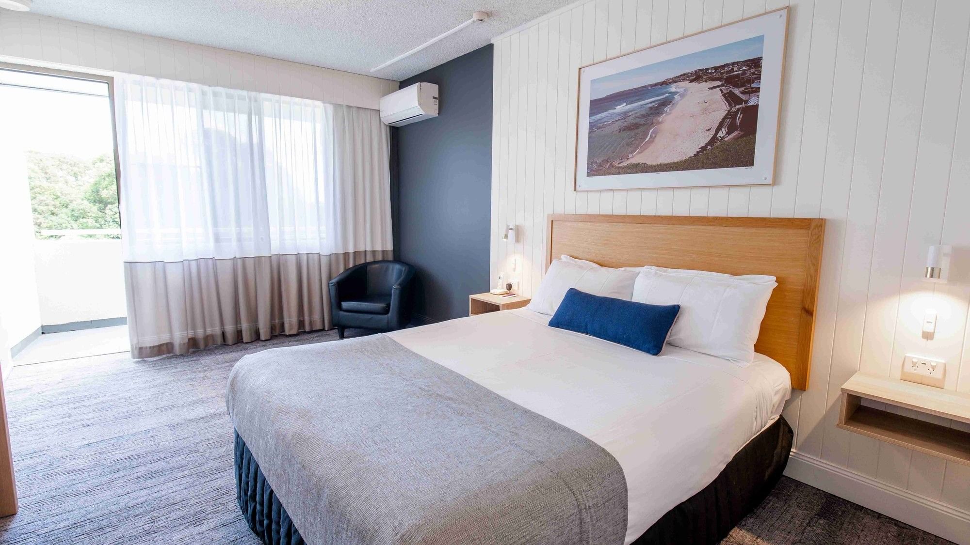 Comfortable bed and beach artwork in Mercure Charlestown room.