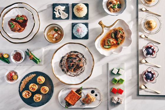 A birds eye view of a spread of asian food on a white tablecloth