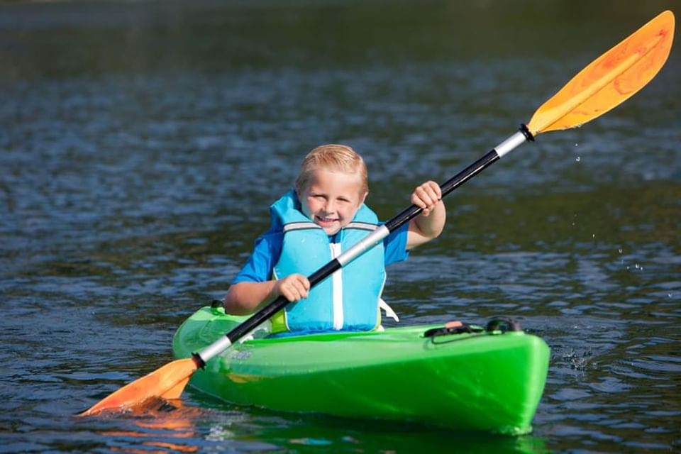 Little boy paddling a kayak on the lake near Alderbrook Resort & Spa