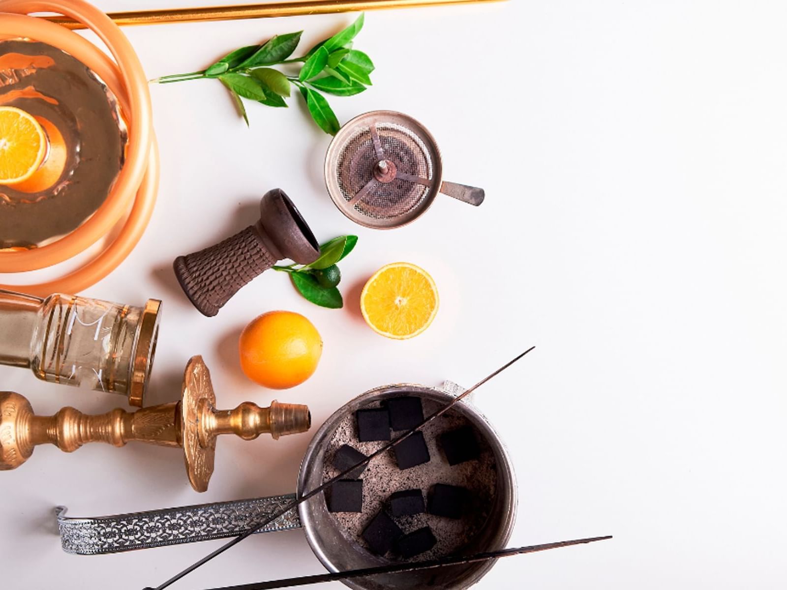Hookah with coals, tongs, and fruit on a white background at Live Aqua Resort & Residence