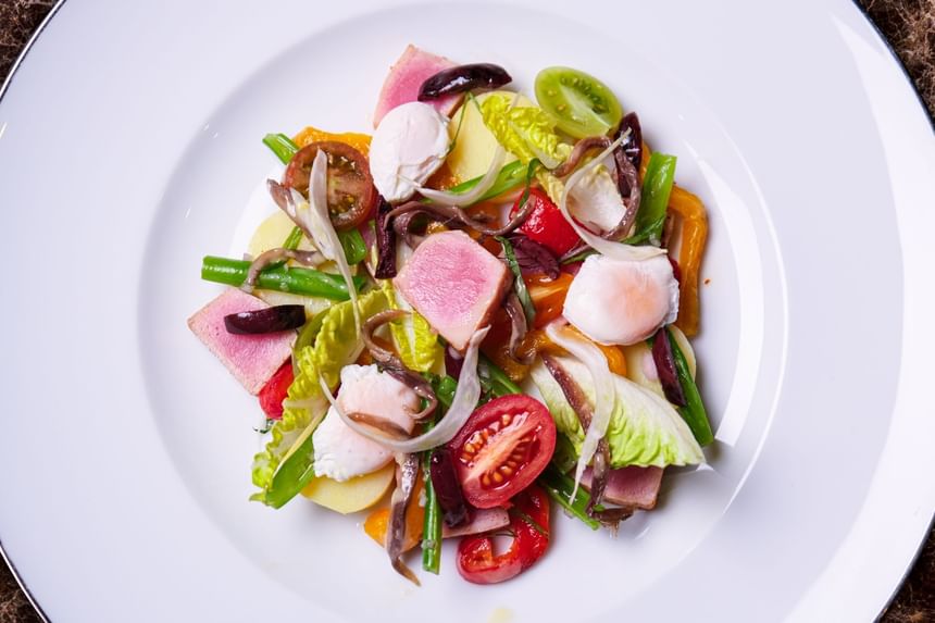 Salad featuring seared tuna, poached eggs, mixed greens, tomatoes, and olives served in Square One at Park Hyatt Saigon