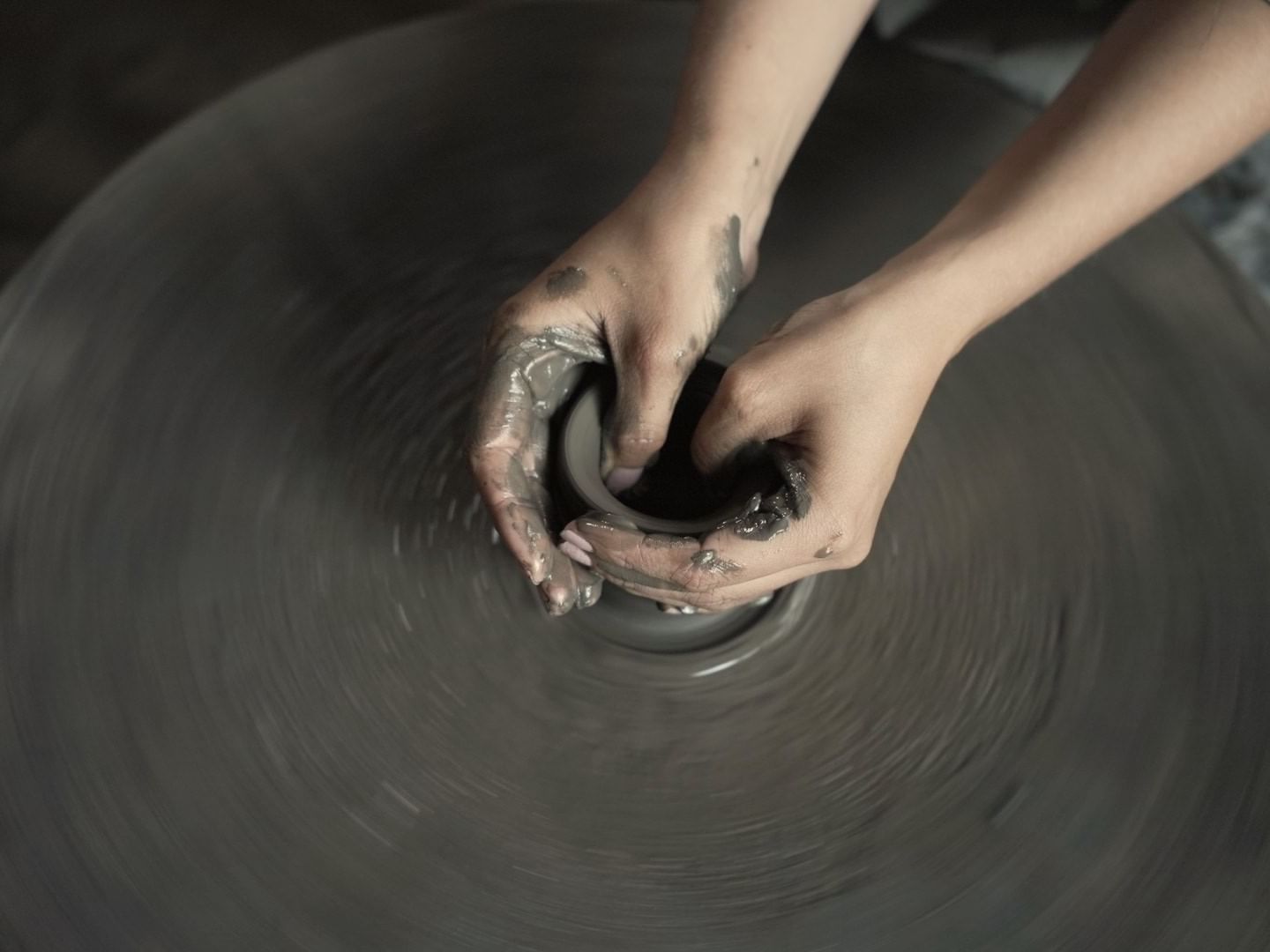 Close-up of hands shaping wet clay on a spinning pottery wheel at Dwarika's Himalayan Wellbeing