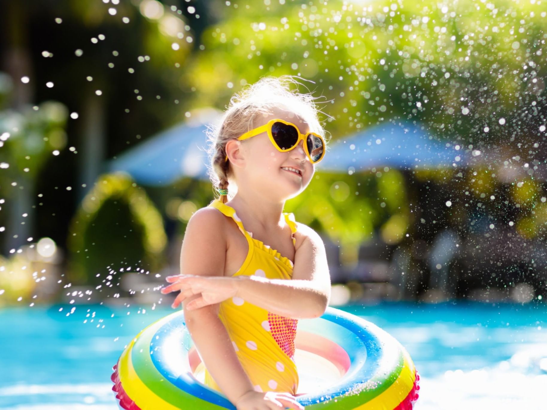 A little girl in a yellow swimsuit having fun in an outdoor pool at The Bethel Inn Resort & Suites