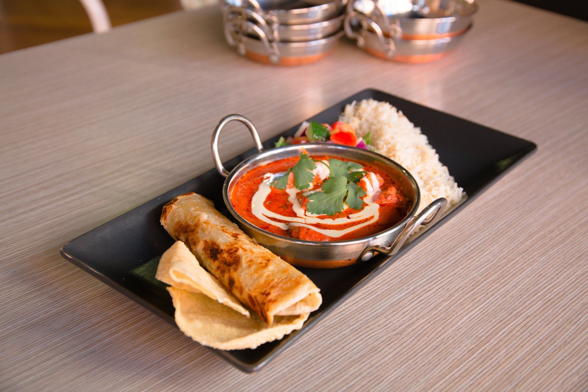 Indian butter chicken, rice, and roti on a black platter served at Ibis Adelaide