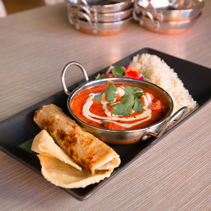 Indian butter chicken, rice, and roti on a black platter served at Ibis Adelaide