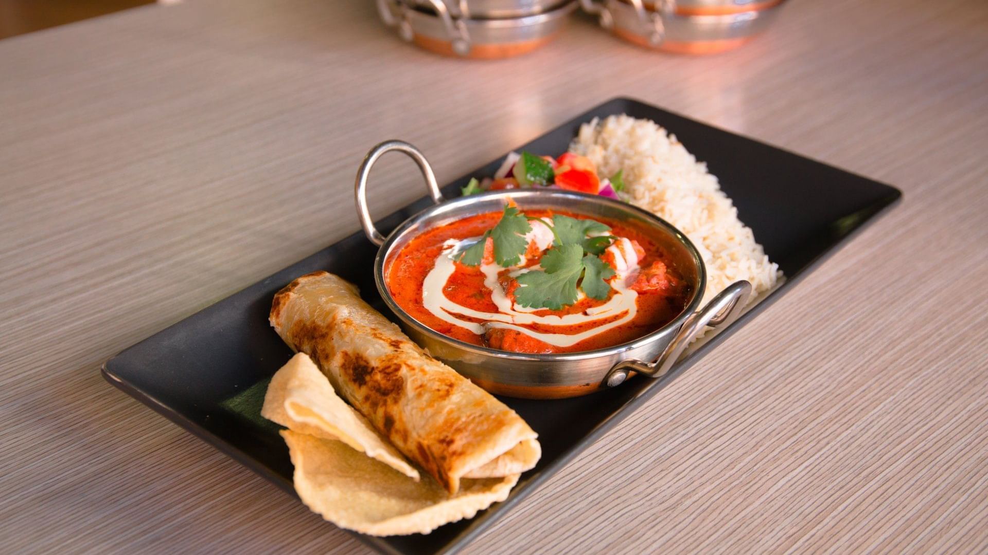 Indian butter chicken, rice, and roti on a black platter served at Ibis Adelaide