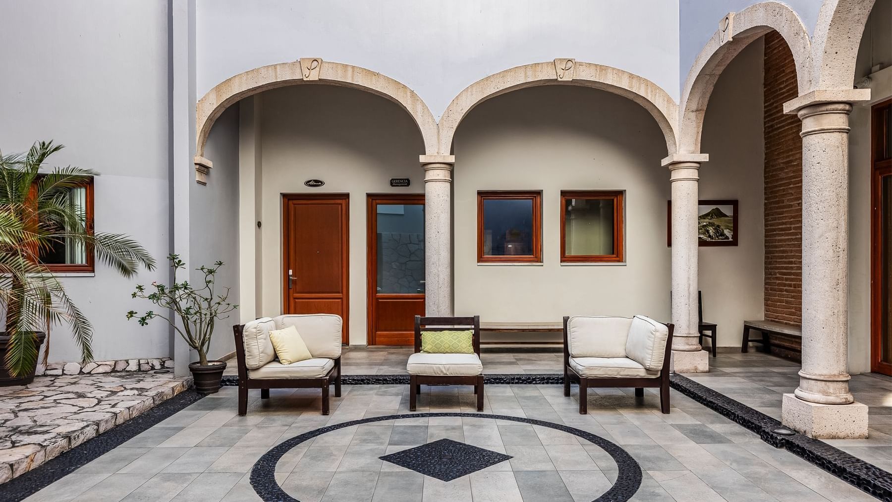 Charming outdoor courtyard featuring elegant arches, comfortable seating, and a tiled patio at Curamoria Collection
