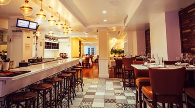 Spice Symphony restaurant with a bar and dining area, featuring checkered floors, stools, and set tables.