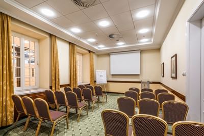Conference room with rows of chairs and a projection screen at the front at Polonia Palace Hotel