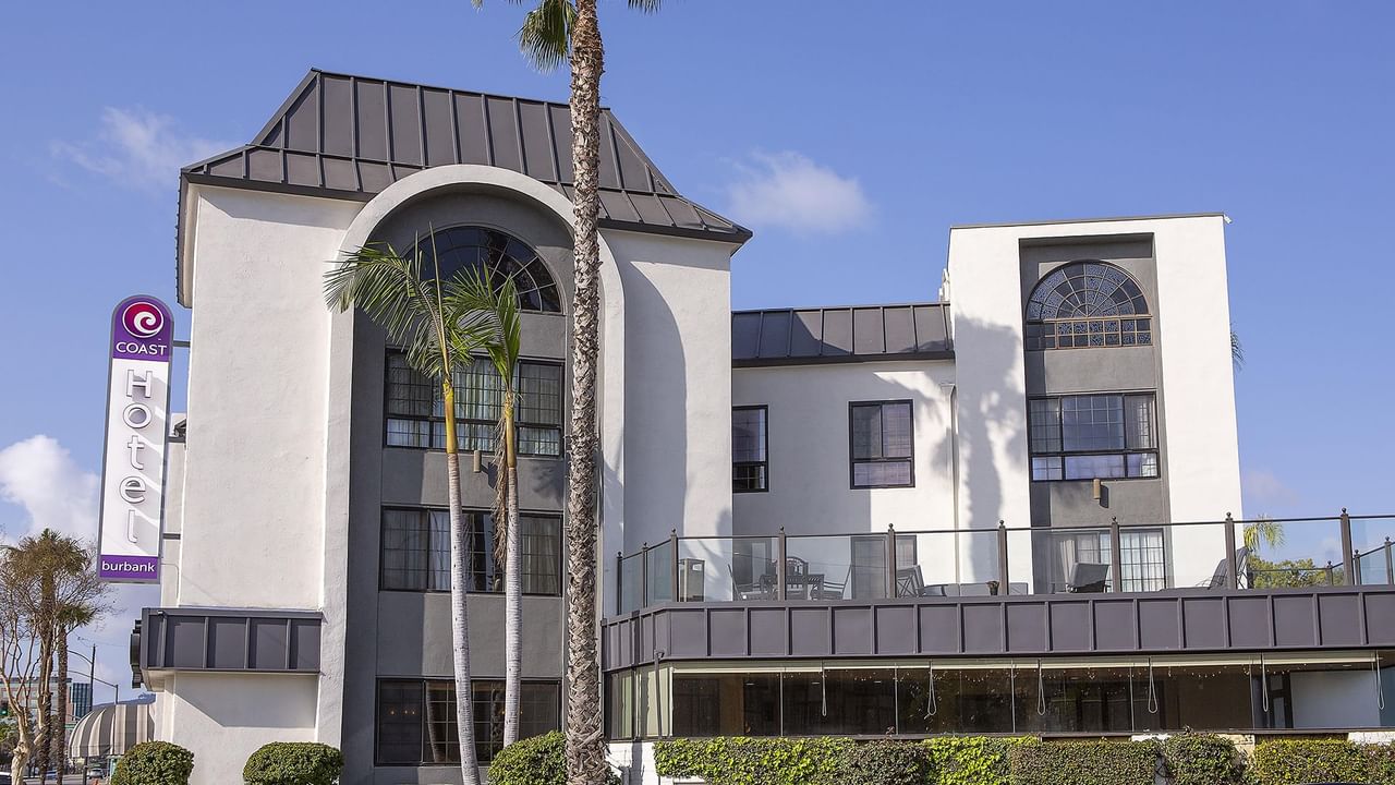 Exterior of Coast Burbank Hotel with palm trees outside the hotel.