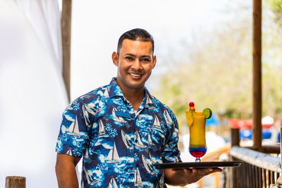 Close-up of a man holding a tray with a cocktail at Hotel Isla Del Encanto