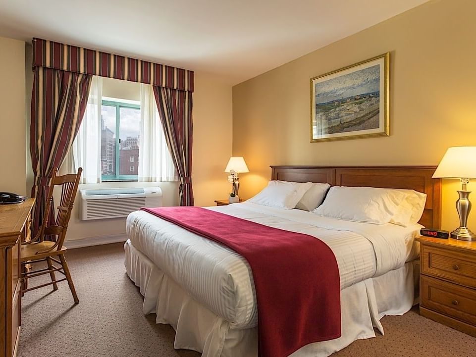 ADA King Room with a large bed, two nightstands, and a window at Chelsea Savoy Hotel in New York.