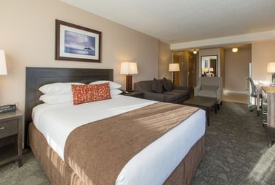 One bedroom Suite with a comfortable king sized bed, a couch and an armchair at Embassy Inn Victoria