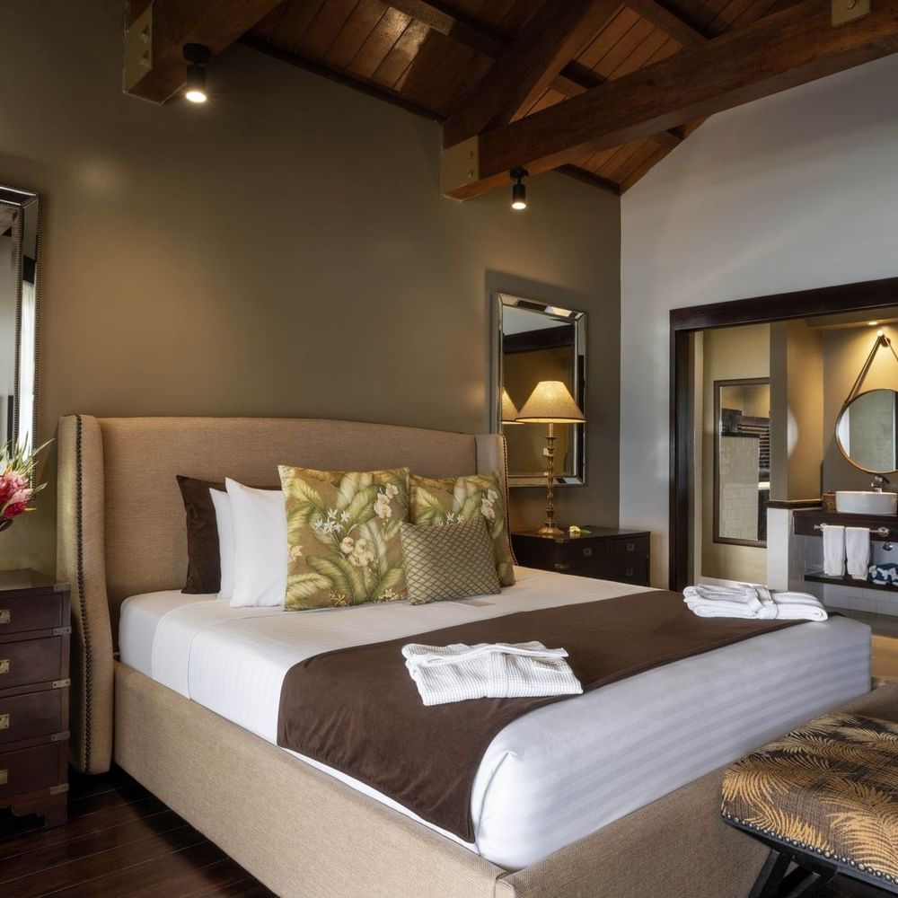 Large bed with pen-plan bathroom includes a white vessel sink & mirror in Erakor Residence at warwick le lagon-vanuatu