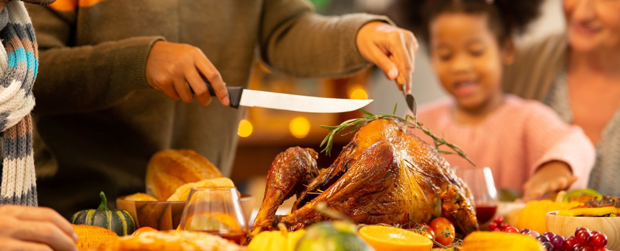 A person cutting a Thanksgicing turkey and child watching