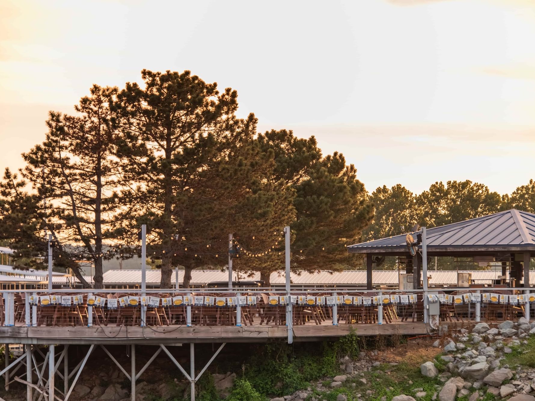 Outdoor patio with empty seating at sunset with string lights and nature view at Eddy’s Lakeside Bar in Shangri-La Resort and Golf Club