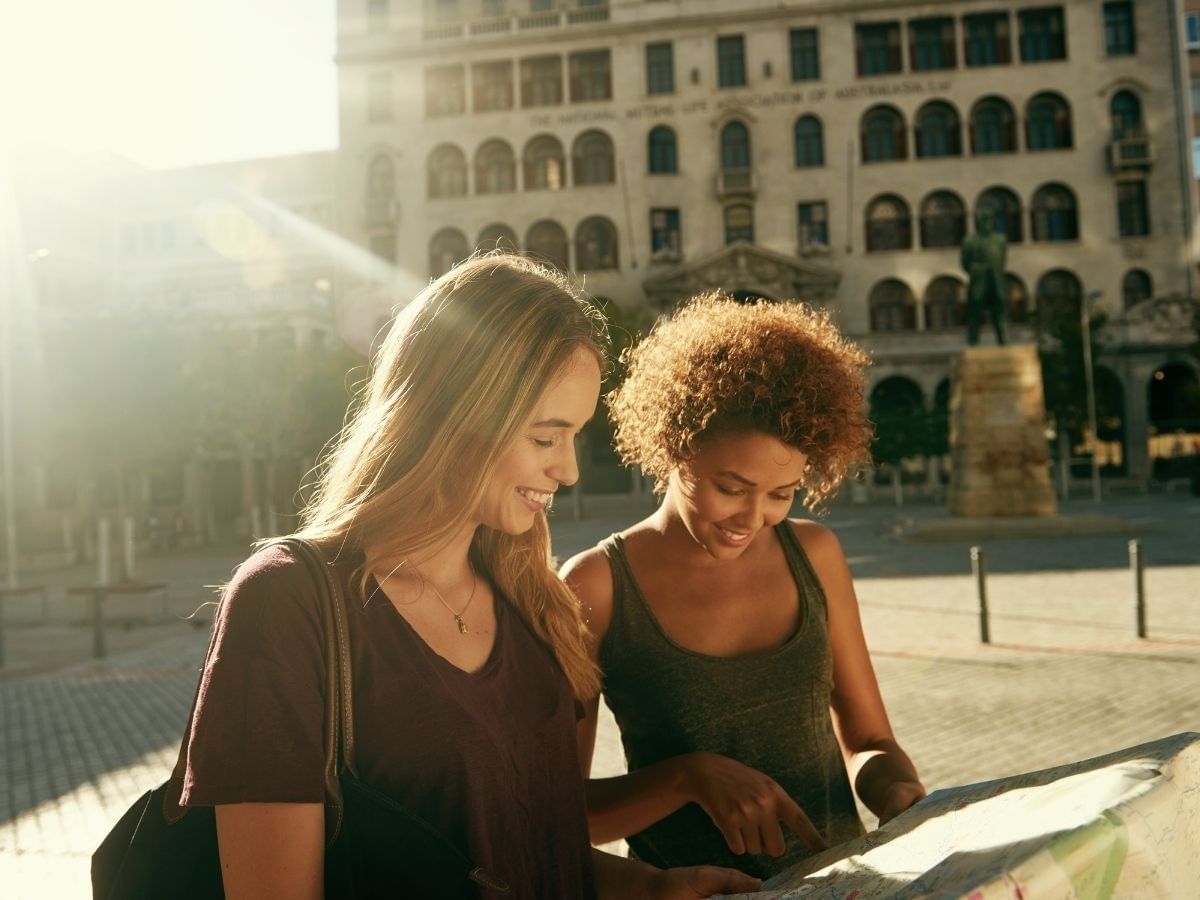two woman looking at a map in a city setting