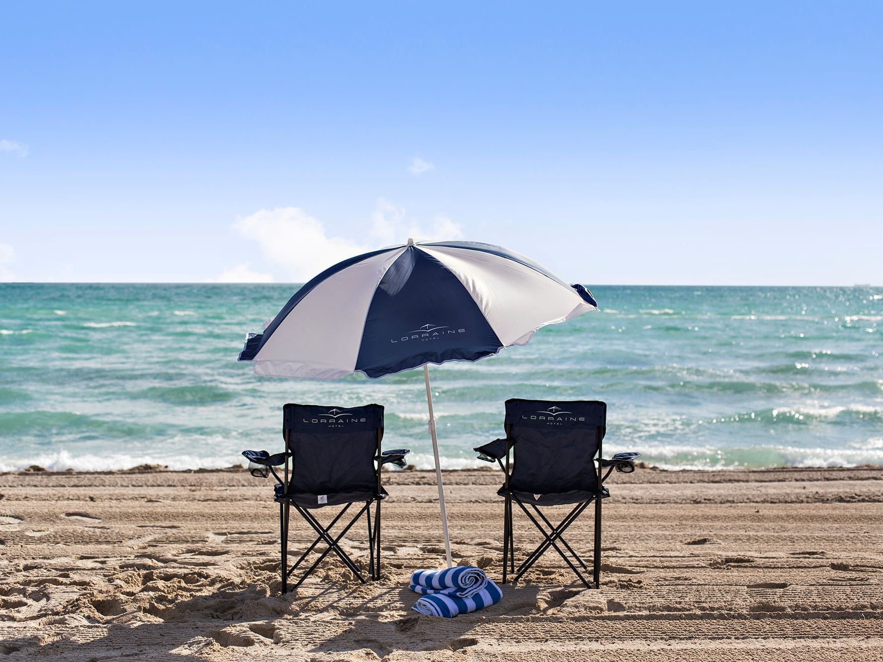 Two lounge chairs & an umbrella by the beach near DOT Hotels