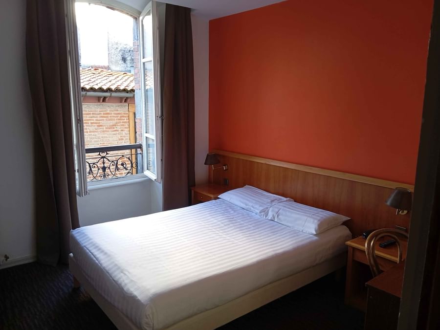 Bed with nightstand by the window in Double Comfort at The Originals Boutique Grand Hotel Saint-Pierre