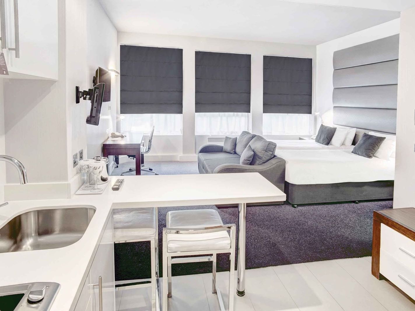 The Two Single Beds Studio at Sandman Signature Newcastle Hotel with two single beds (with premium pillow-top), one pull-out sofa bed, a flat-screen tv and a pantry with white pantry cupboards and furniture