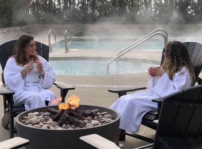 2 ladies having coffee by the outdoor fireplace, Aava Whistler