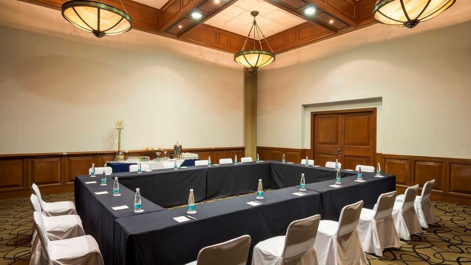 Professional meeting room set up in a U-shape with white chair covers at Camino Real Puebla Angelopolis