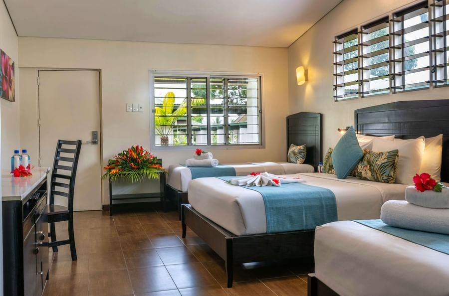 Three hotel beds with tropical decor and amenities in a Tokatoka Resort room.