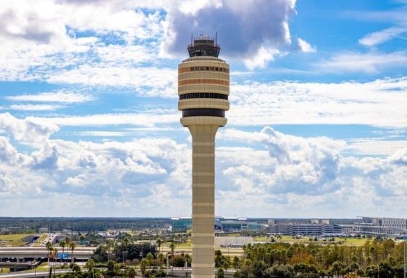 The navigation tower at MCO airport against a blue, cloudy sky.