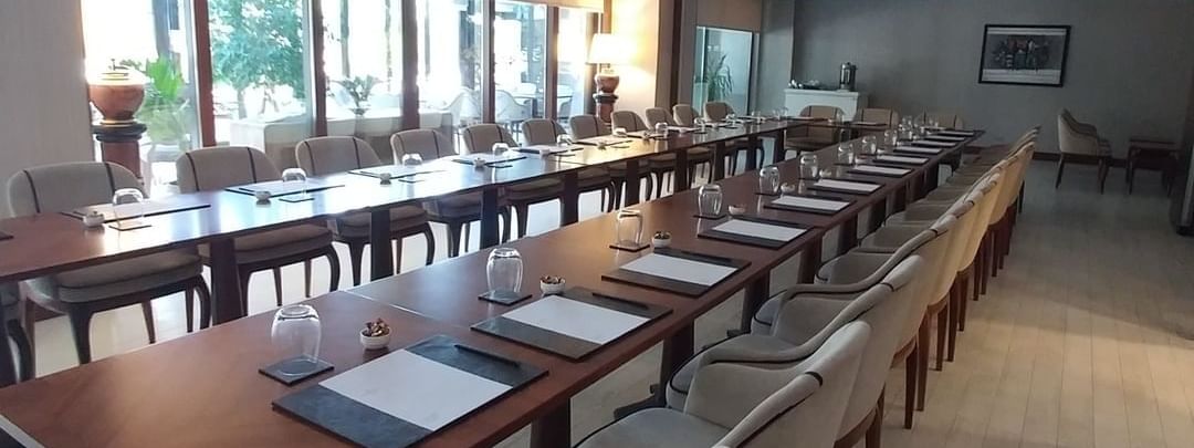 Row of chairs by a long table under a recessed ceiling near large windows in Kugu 2 Hall at Warwick Ankara