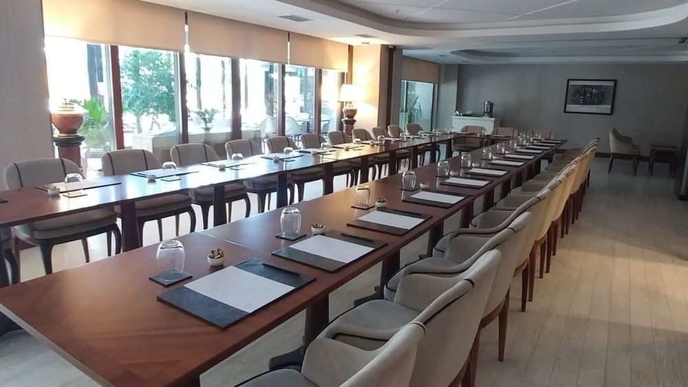 Row of chairs by a long table under a recessed ceiling near large windows in Kugu 2 Hall at Warwick Ankara