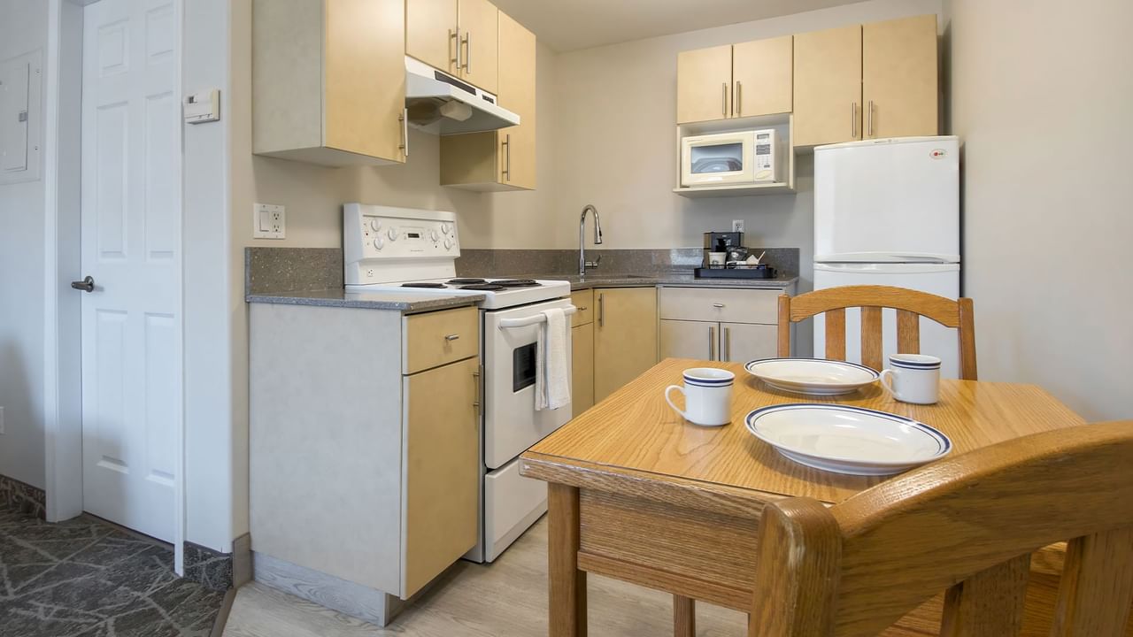 A small kitchen area with gas range, microwave, refrigerator and dining area