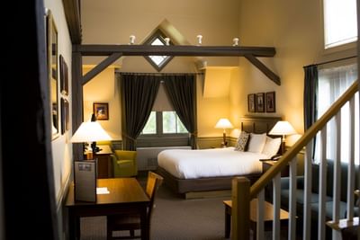 Broad king room with reading nook, large bed, and stairway