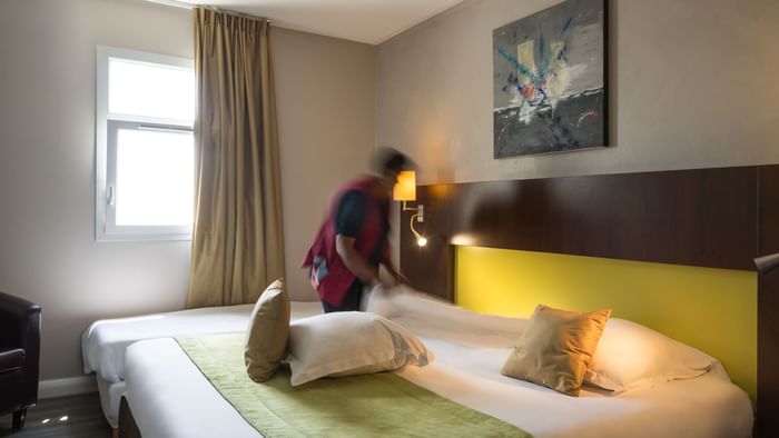 A maid preparing a bed in a room at Hotel Novella Premium