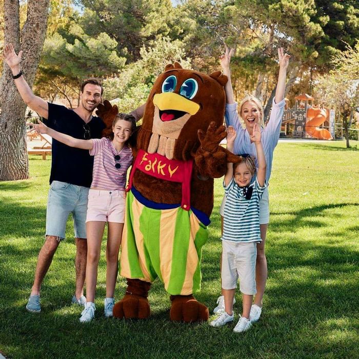 Family posing for a photo with a mascot at Falkensteiner Hotels
