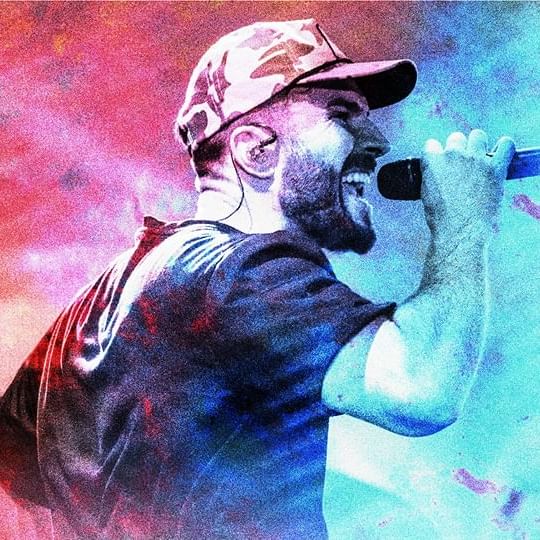 Sam Hunt wearing a hat singing into a microphone