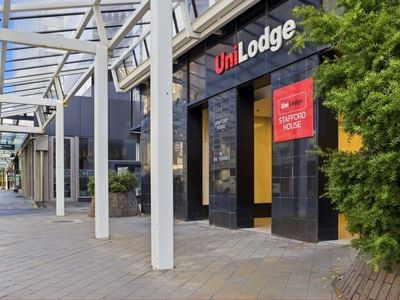 Entrance of UniLodge Stafford House with canopy and cars parked nearby.