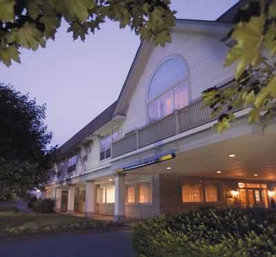 Exterior view of Farmington Inn and Suites entry portico with white pillars under a twilight sky