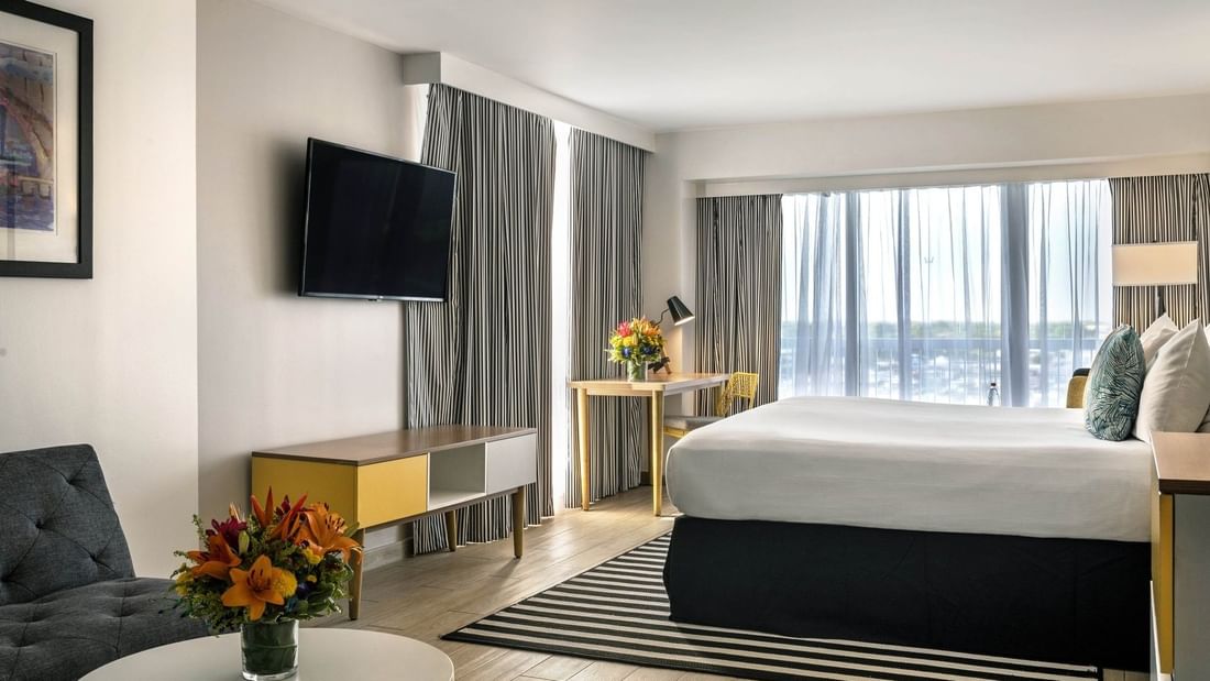 King bed by a striped rug under a TV with a desk and chair in Harbour Premium Balcony at Warwick Paradise Island Bahamas