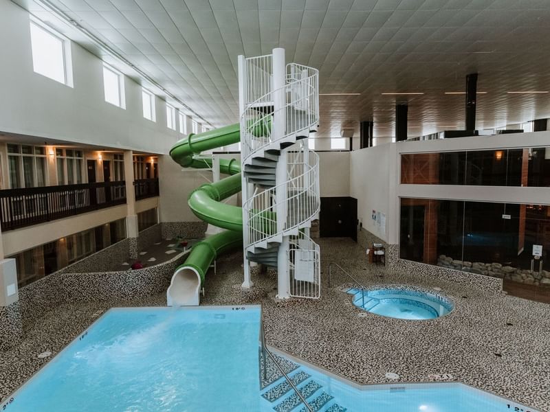 Indoor pool with green waterslide and jacuzzi