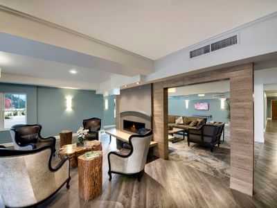 A stylish modern lounge area with a fireplace and wood floors at The Stanley Hotel, with chairs and sofas